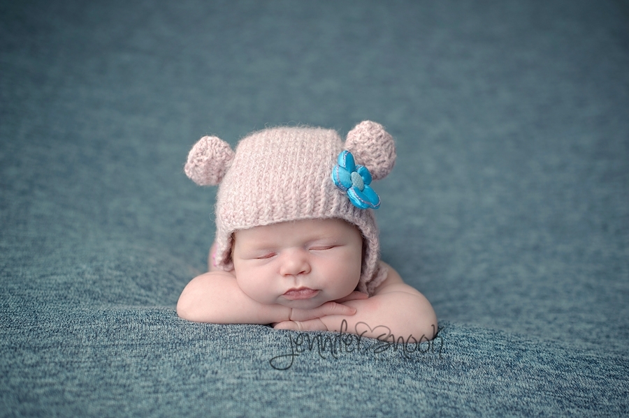 newborn with hat on propped up on hands